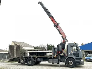 Camion plateau équipé d'une grue télescopique extensible Fassi, vue de trois quarts.